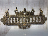 An ornate brass horizontal wall hanging featuring a row of ten standing Hindu deities or figures, flanked by decorative motifs and elephants, on a light background.